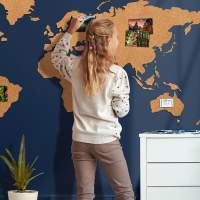Mädchen pinnt Reisefotos an XXL Kork Weltkarte
